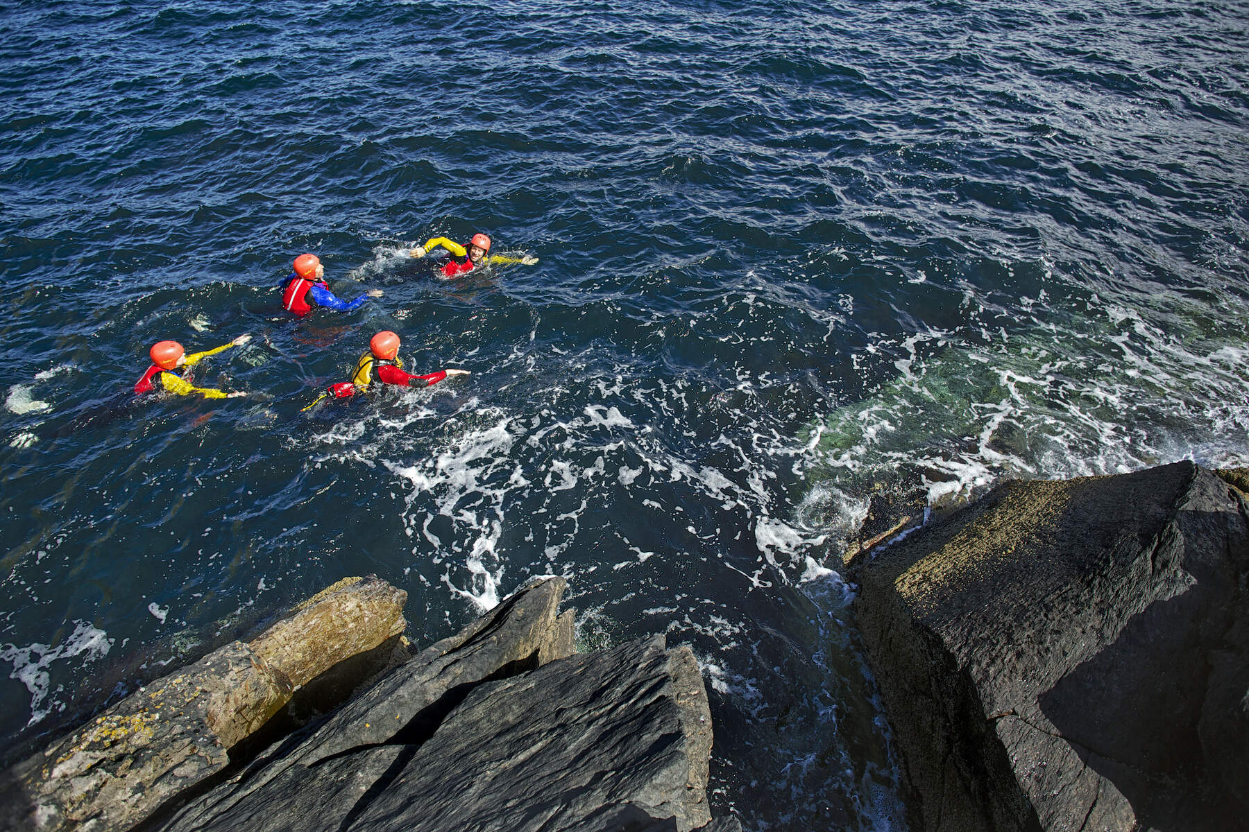 Tijdens coasteering in Noord-Ierland varieer je tussen zwemmen en rotsen beklimmen.