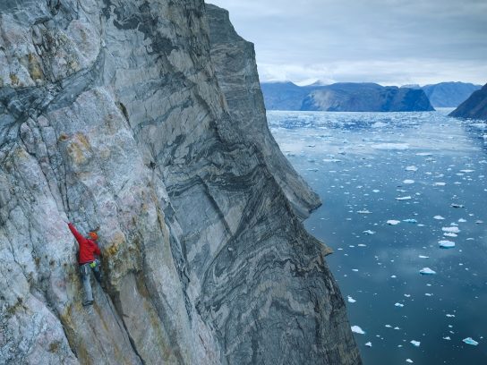 Alex Honnold beklimt de Ingmikortilaq met bergen en water op de achtergrond.