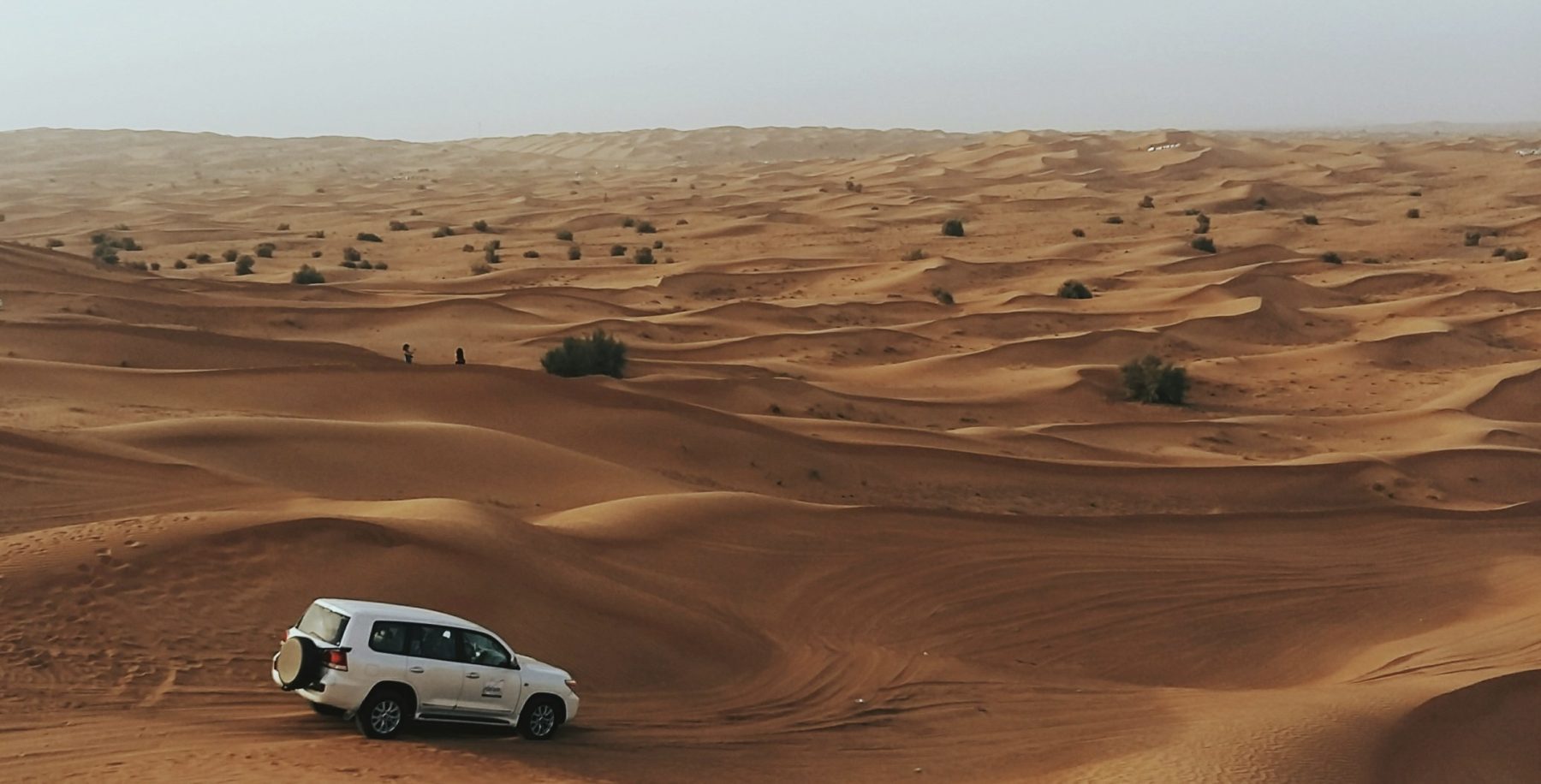 Een auto rijdend door de woestijn in Dubai, een geweldige bestemming voor een winter-zonvakantie.