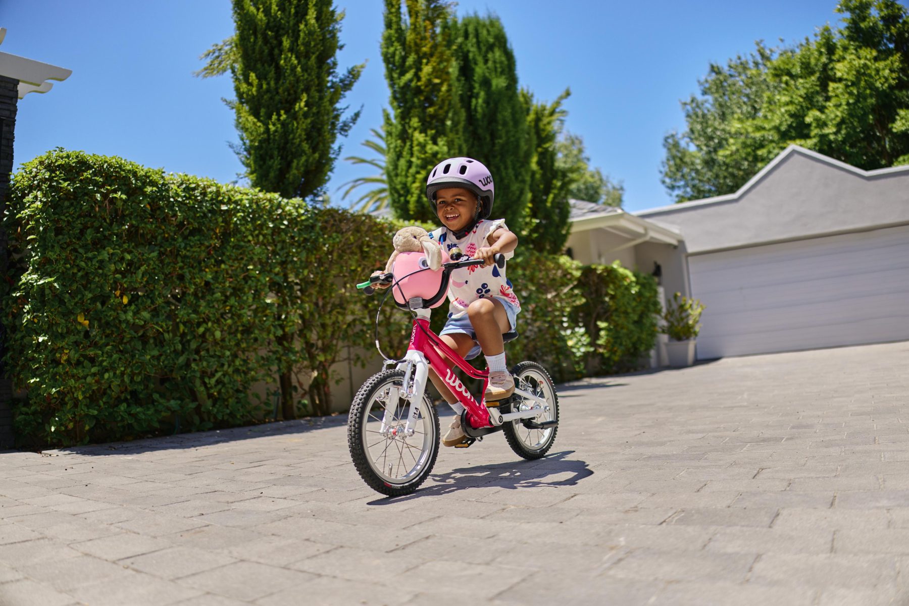 Een klein meisje op een fiets van woom met een POP-kinderfietsmandje erop in de kleur marshmallow pink.