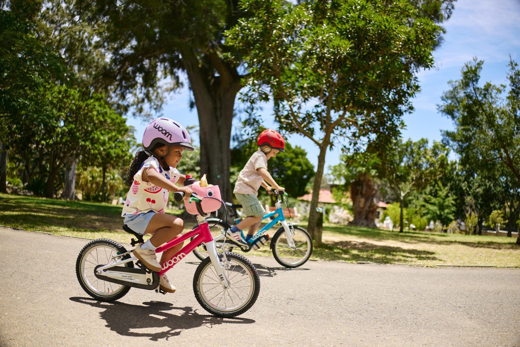 Twee kinderen fietsen op een woom GO-fiets met een READY-helm op.