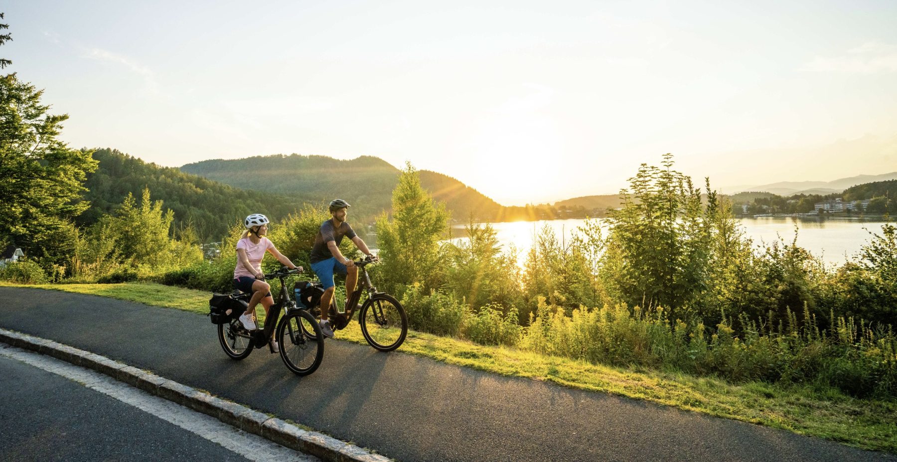 Twee fietsers rijden op een zonnige dag langs een meer in Karinthië tijdens het fietsevenement Velovista.