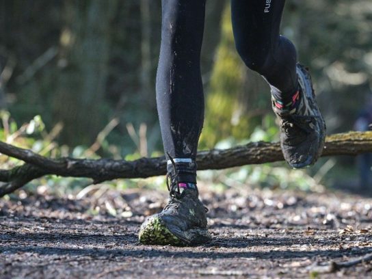 Actiefoto van de benen van een trailrunner op een bospad