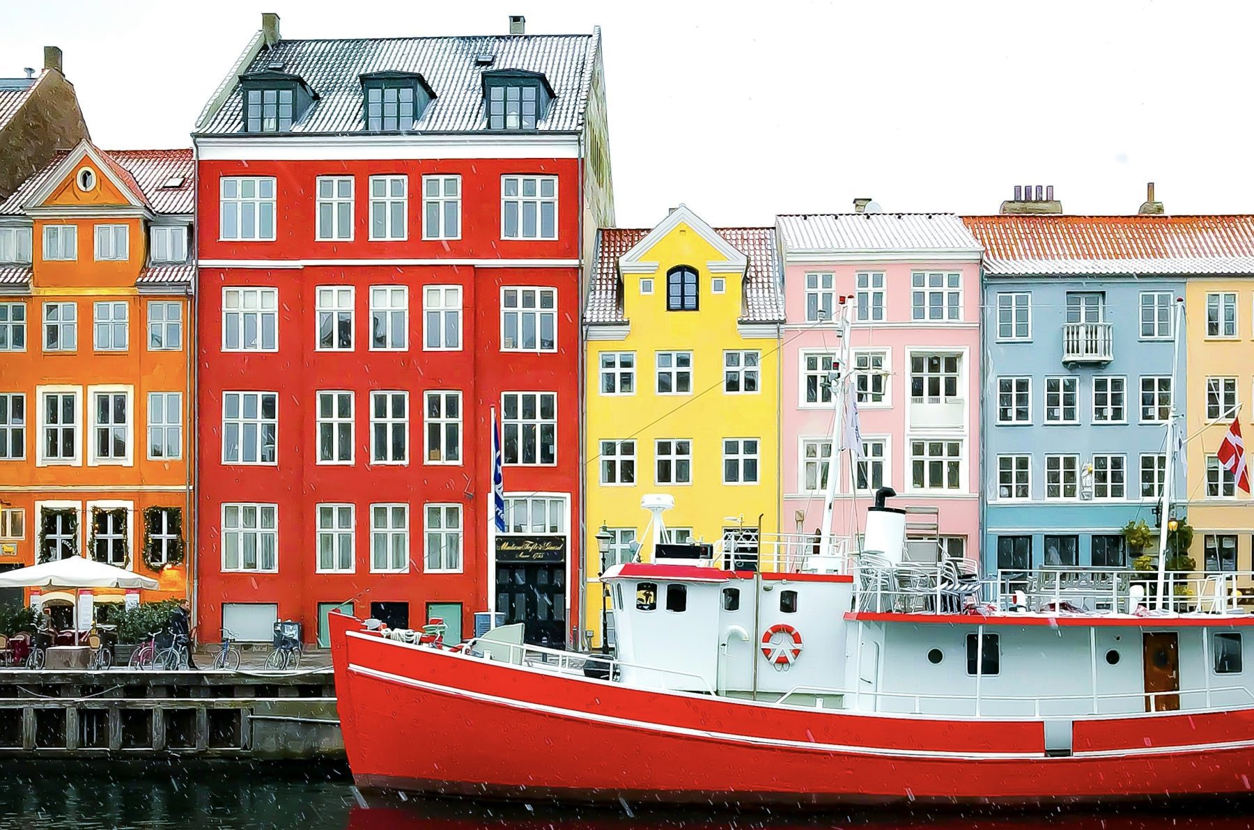 Gekleurde huizen aan de haven van Kopenhagen met op de voorgrond een boot tijdens een regenachtige dag.