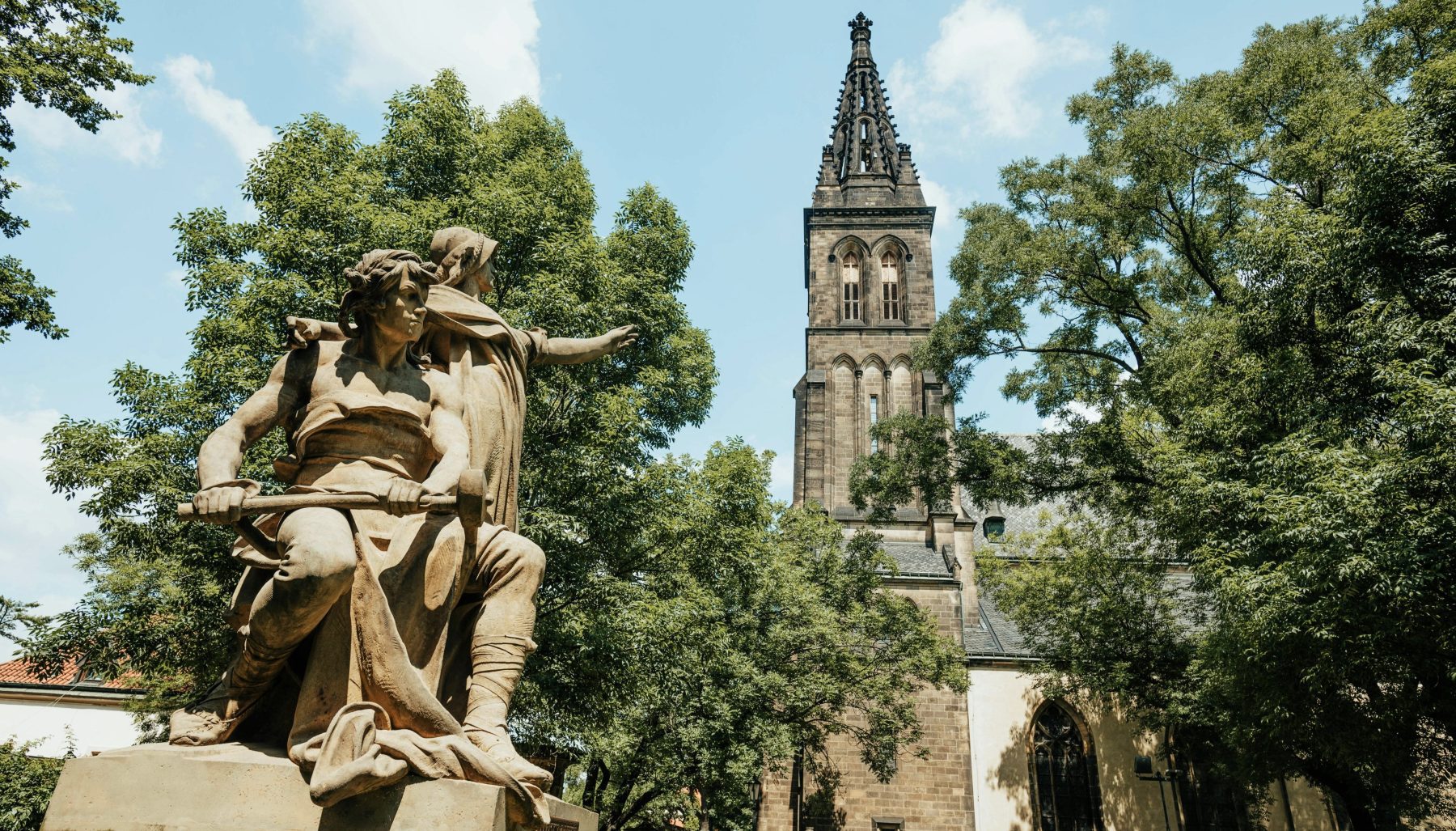 Een standbeeld met op de achtergrond de Sint-Petrus-en-Pauluskerk in de Praagse wijk Vyšehrad.