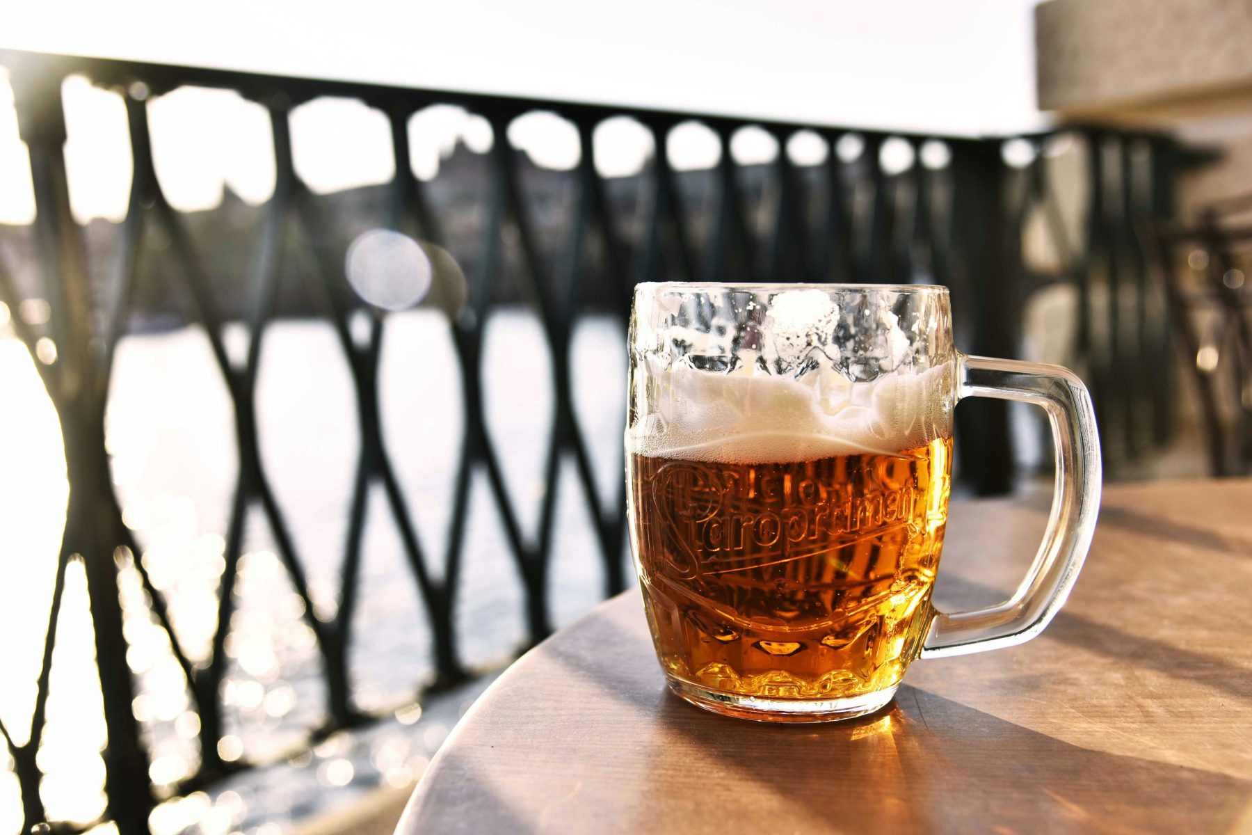 Een groot glas bier op een tafel op een terras aan het water in Praag.