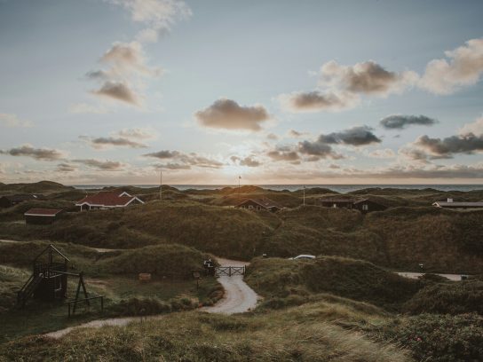 Een duinachtig gebied in Denemarken met de zee op de achtergrond.