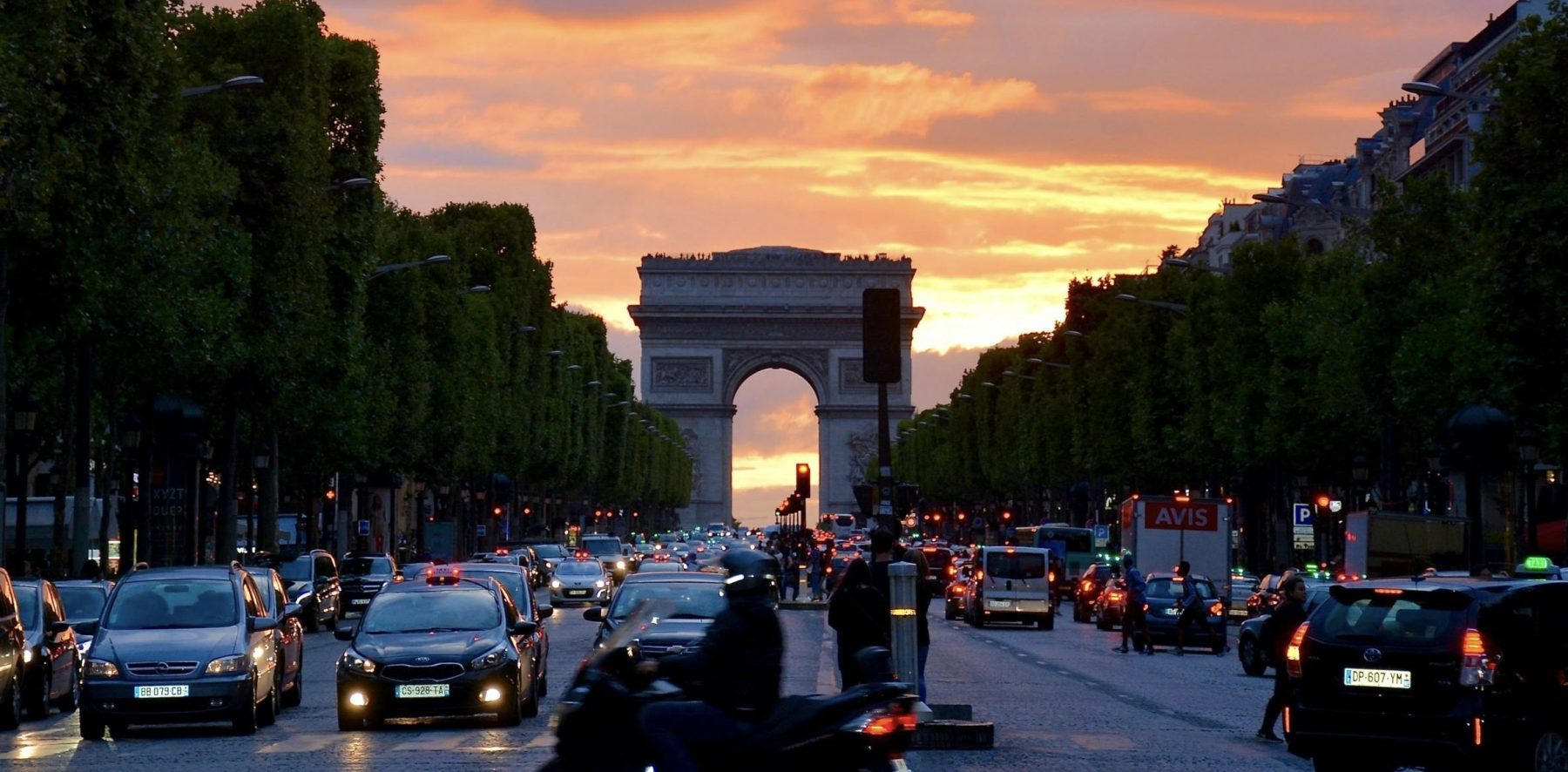 De Champs-Élysées met auto's op de voorgrond tijdens zonsondergang.