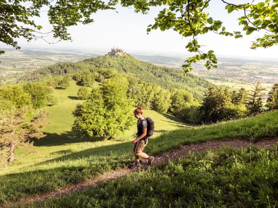 Traufgang Zollernburg-Panorama, Albstadt-Onstmettingen, Baden-Württemberg, Germany: A female hiker with the Hohenzollern Castle in the background. Meerdaagse wandelroutes Duitsland