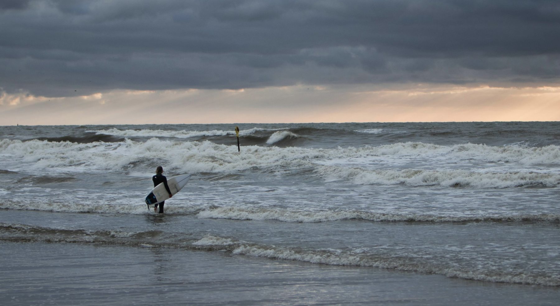Persoon met een surfboard in de zee bij Scheveningen.