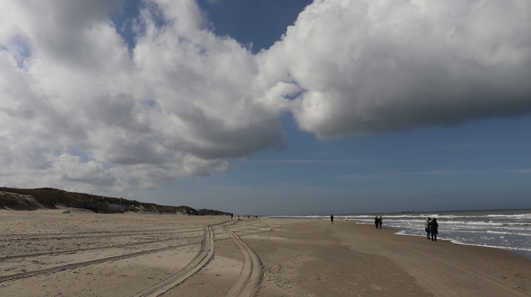 Mensen wandelend op het strand van Texel, wat een leuke activiteit is om te doen tijdens een nachtje weg aan zee.