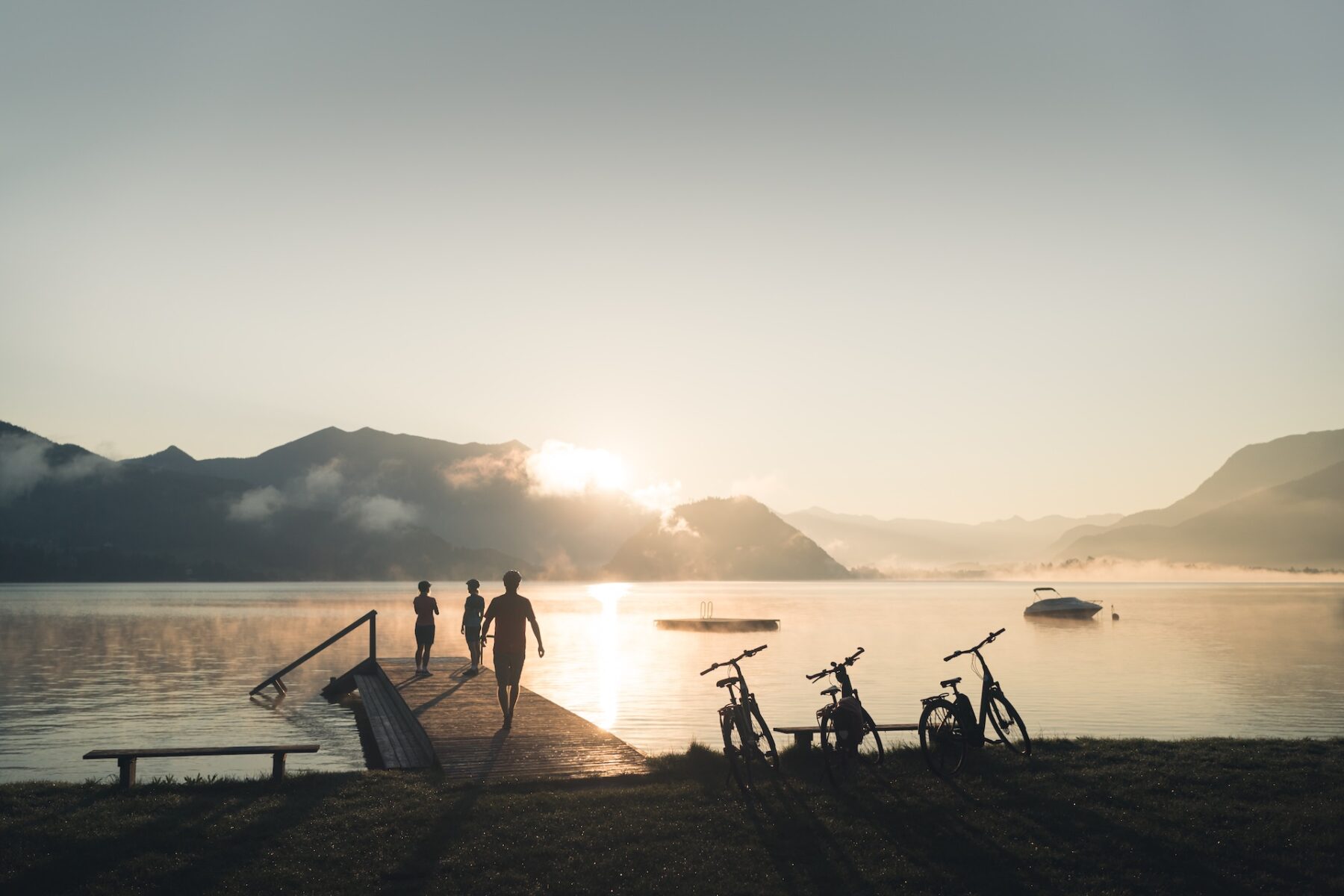 Radfahrer betrachten vom Steg des Gemeindebades Gschwandt in Strobl aus den Wolfgangsee im Salzkammergut.