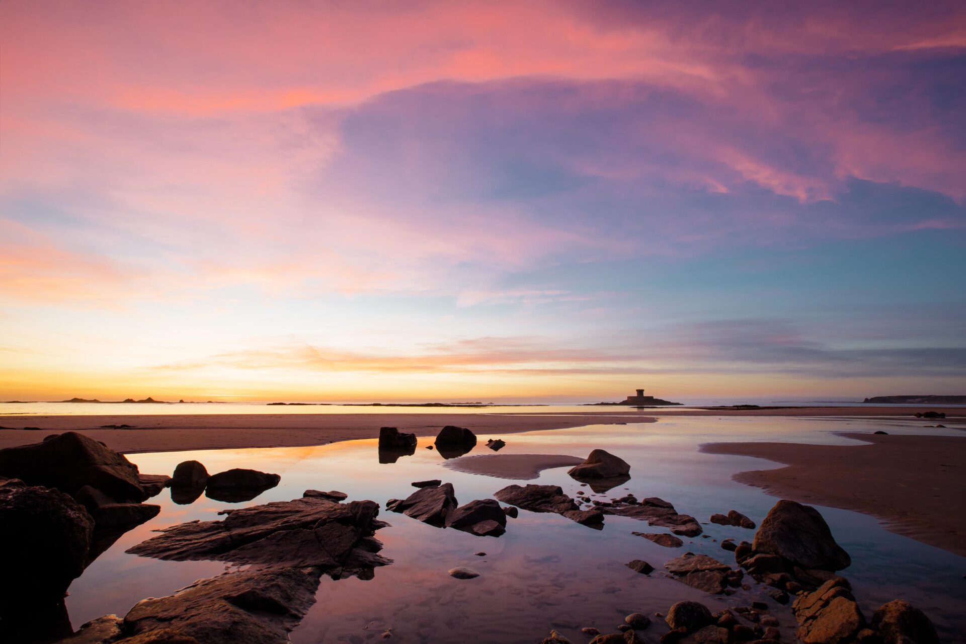 Een kleurrijke zonsondergang boven de La Rocco-toren bij St. Ouen's Bay.